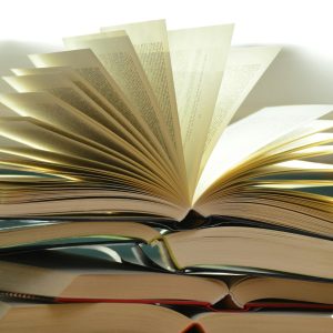 A close-up of a stack of open books with pages fanned out, capturing a study atmosphere.